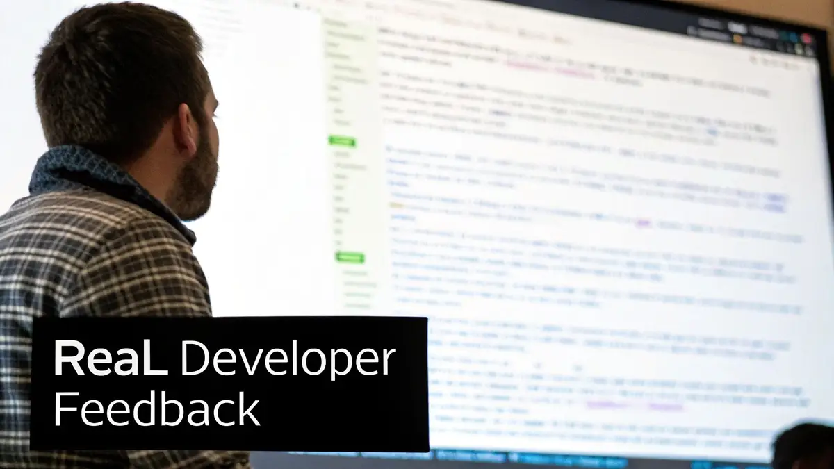 A developer in a plaid shirt reviews code on a large screen, with 'ReaL Developer Feedback' text overlay.