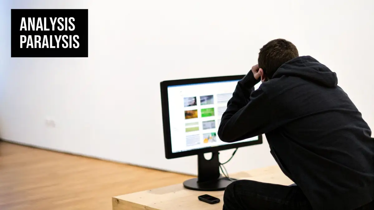 A person in a black hoodie sits frustratedly in front of a computer, with 'ANALYSIS PARALYSIS' text.